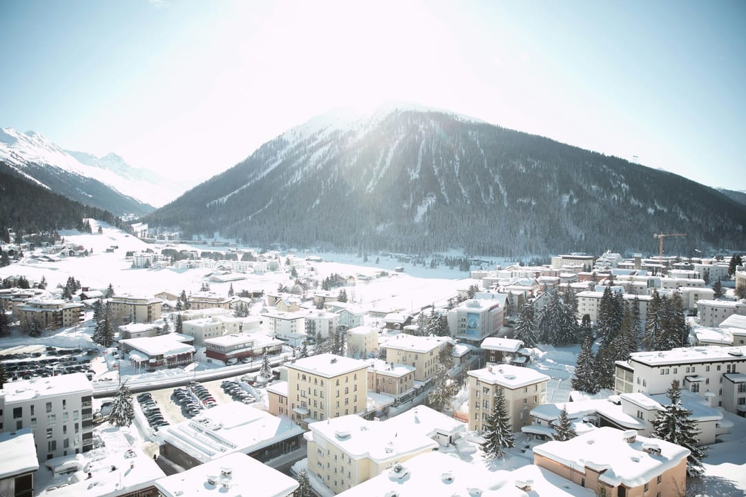 Verschneite Wohnhäuser in Davos vor dem Berg